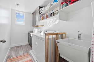 Laundry area featuring light wood-type flooring, cabinet space, and washing machine and dryer