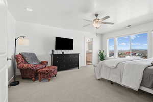 Bedroom with light carpet, ensuite bathroom, and ceiling fan