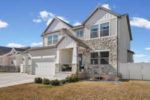 Craftsman-style home with board and batten siding, stone siding, a gate, concrete driveway, and a garage