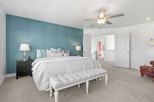 Bedroom featuring a decorative wall, light colored carpet, and a ceiling fan