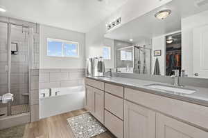 Bathroom with double vanity, a shower stall, a spacious closet, and a garden tub