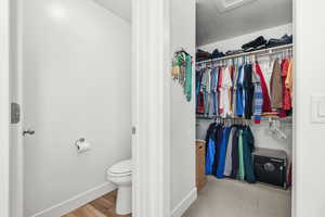 Bathroom with a spacious closet, a textured ceiling, and light wood finished floors