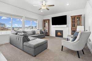Carpeted living room featuring ceiling fan, a fireplace, and recessed lighting