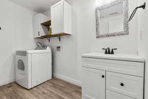 Laundry room with washer / dryer, cabinet space, and light wood-type flooring