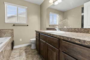 Bathroom with vanity, a garden tub, and light tile patterned floors