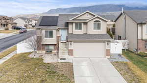 View of front of house featuring roof mounted solar panels, a gate, driveway, an attached garage, and stucco siding