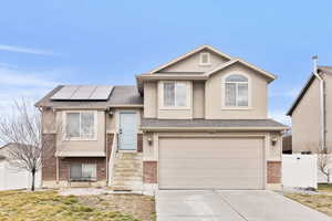 View of front of home featuring brick siding, concrete driveway, and stucco siding
