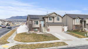 View of front of home with roof mounted solar panels, a residential view, a garage, concrete driveway, and a mountain view