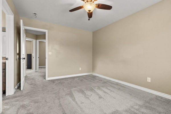 Empty room featuring light colored carpet and a ceiling fan