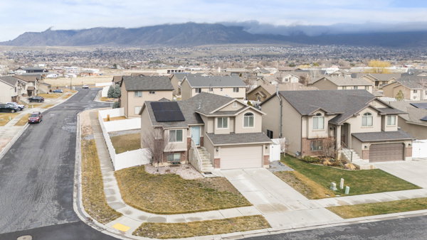 View of front of property featuring roof mounted solar panels, concrete driveway, a residential view, an attached garage, and a mountain view