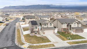 View of front of property featuring roof mounted solar panels, concrete driveway, a residential view, an attached garage, and a mountain view