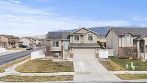View of front of property featuring a gate, solar panels, a residential view, driveway, and an attached garage