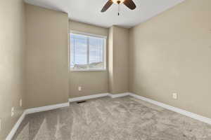 Empty room featuring light colored carpet and ceiling fan