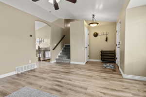 Foyer with vaulted ceiling, ceiling fan, light wood-type flooring, and arched walkways