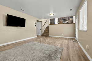 Unfurnished living room with stairway and light wood-type flooring