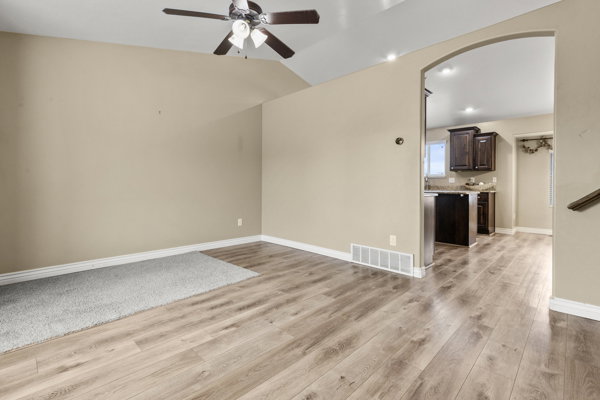 Unfurnished living room with a ceiling fan, lofted ceiling, light wood-style floors, arched walkways, and recessed lighting
