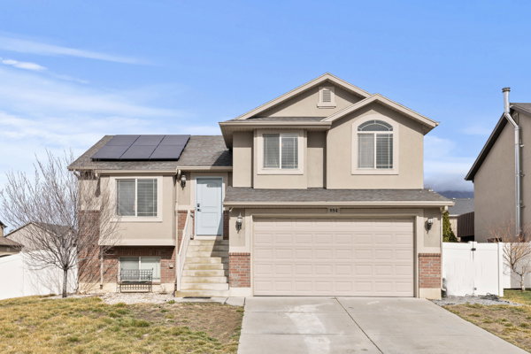 View of front of home with a gate, brick siding, concrete driveway, and stucco siding