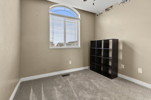 Empty room with light carpet and a ceiling fan