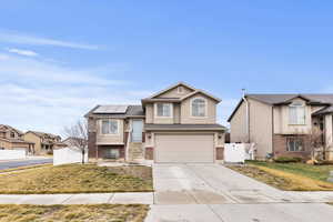 View of front of home featuring a gate, solar panels, concrete driveway, stucco siding, and an attached garage
