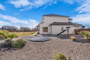 Back of property with a playground and stucco siding