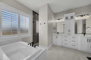 Full bathroom featuring double vanity, a garden tub, a shower stall, and light marble finish flooring
