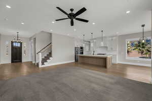 Unfurnished living room with suspended lighting, a ceiling fan, and dark wood finished floors