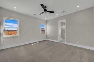 Unfurnished bedroom with light carpet, a ceiling fan, recessed lighting, ensuite bathroom, and a decorative wall