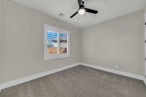 Unfurnished room featuring dark colored carpet and a ceiling fan