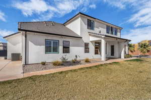 Rear view of property with a lawn, stucco siding, a patio area, and a tile roof
