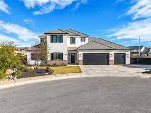 View of front of house featuring a garage, brick siding, driveway, stucco siding, and a tiled roof