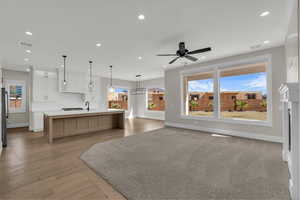 Kitchen with open floor plan, a spacious island, dual tone cabinetry, light wood-style floors, and ceiling fan