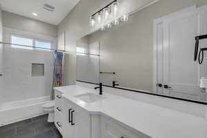 Bathroom with vanity, shower / tub combo with curtain, and dark tile patterned floors
