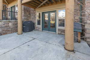 Back of condo with stone siding, a patio area, and french doors