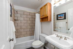 Bathroom featuring toilet and tub/shower combination with curtain
