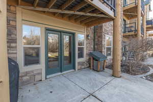 Back of condo with stone siding, a patio area, and french doors