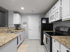 Kitchen with white appliances, light stone countertops, white cabinets, light tile patterned floors, and recessed lighting