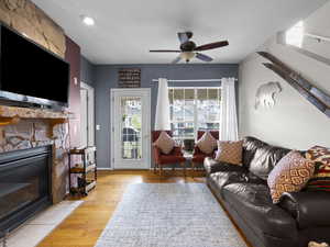 Living area featuring light wood-type flooring, a ceiling fan, and a fireplace