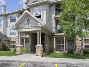 View of front of home with stone siding, a balcony, and a front lawn