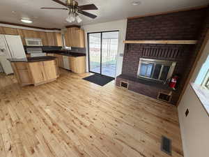 Kitchen featuring a center island, white appliances, light wood-style floors, dark countertops, and ceiling fan