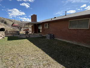 Rear view of property with a yard, brick siding, a chimney, a mountain view, and a patio area