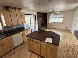 Kitchen featuring light wood-style floors, dishwasher, a kitchen island, open floor plan, and recessed lighting