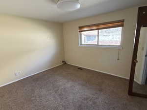 Unfurnished room featuring dark colored carpet and baseboards