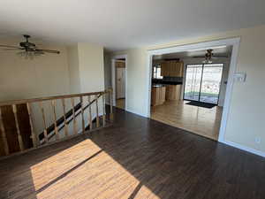 Unfurnished living room with ceiling fan and dark wood-style flooring