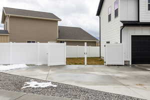 View of side of home featuring a shingled roof and concrete driveway