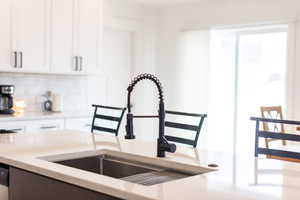 Kitchen featuring tasteful backsplash, light stone counters, and two tone color scheme