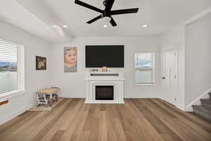 Unfurnished living room with wood-type flooring, a ceiling fan, a glass covered fireplace, and recessed lighting
