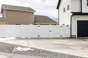 View of side of home with a gate, roof with shingles, and driveway