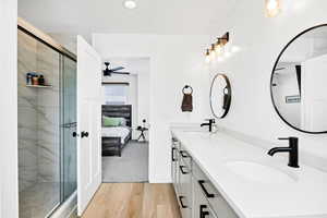 Bathroom featuring connected bathroom, double vanity, a shower stall, and light wood-type flooring