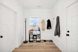 Mudroom featuring light wood-style flooring and wooden walls