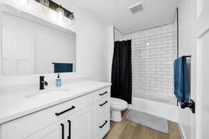 Full bathroom with vanity, shower / bath combo with shower curtain, and light wood-type flooring
